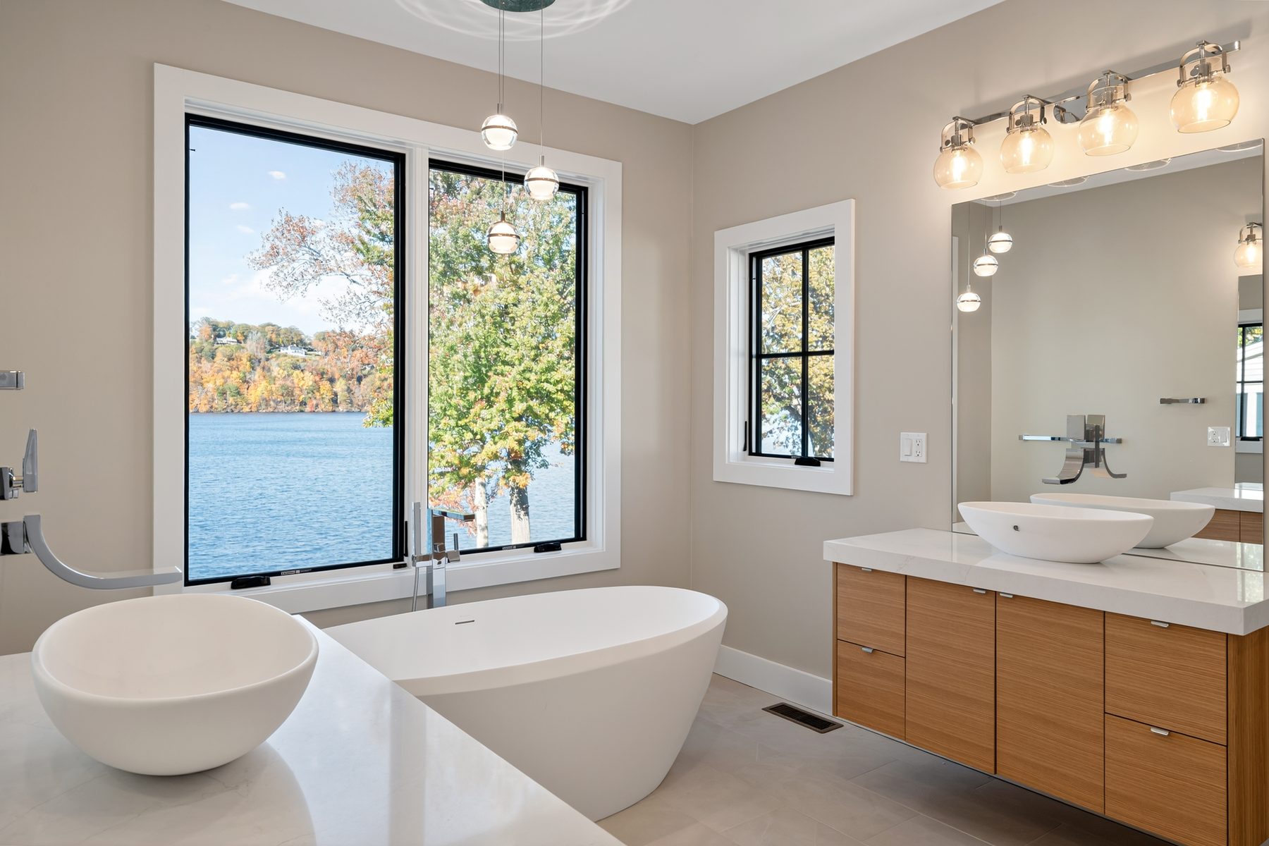 Primary bath with a freestanding soaking tub set beneath lake-view windows and a floating wood vanity - 148 North Lake Shore in Candlewood Shores on Candlewood Lake