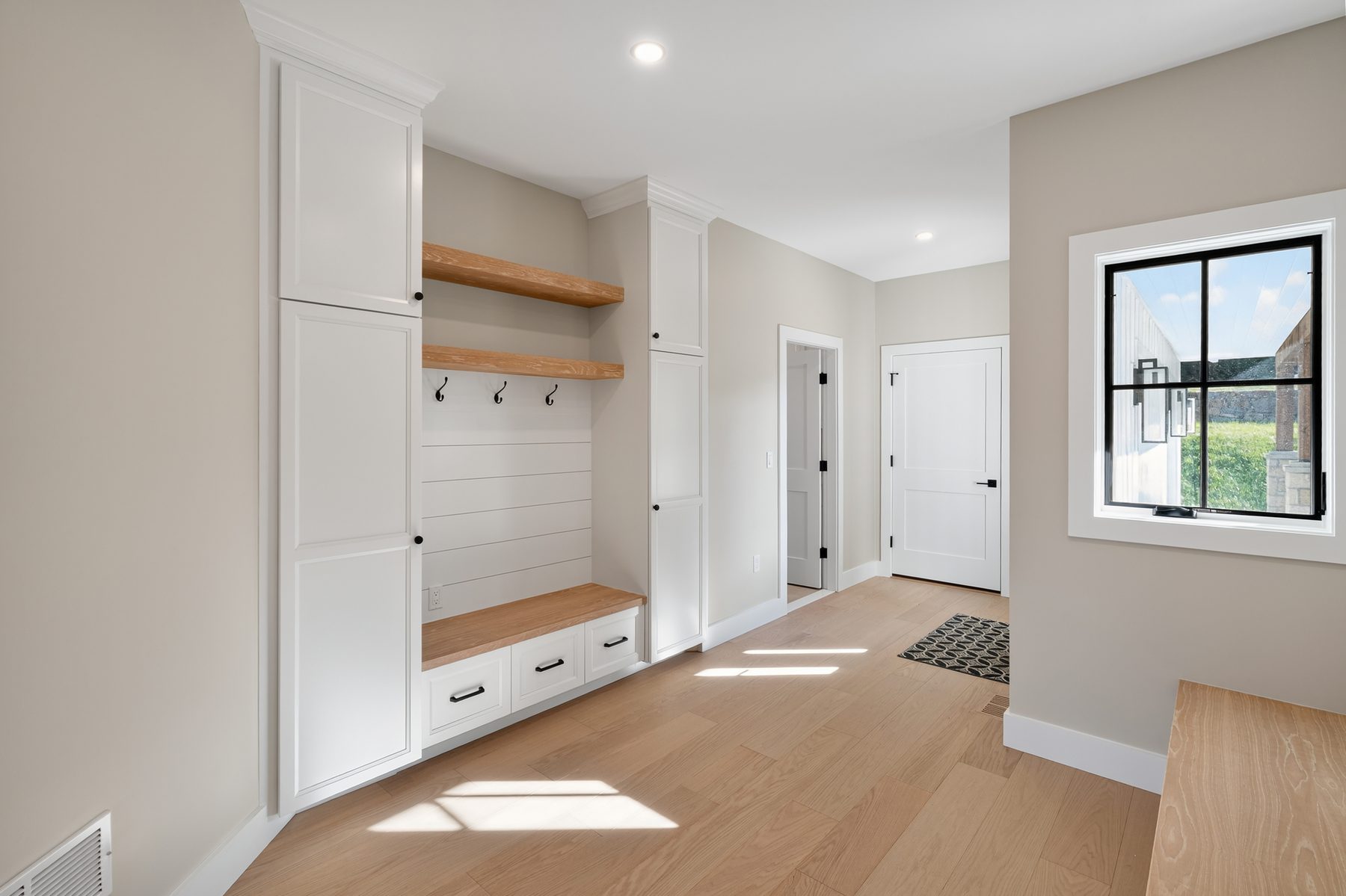 Mudroom drop zone with built-in white lockers, a wood bench, shiplap with coat hooks, and oak floating shelves - 148 North Lake Shore in Candlewood Shores on Candlewood Lake