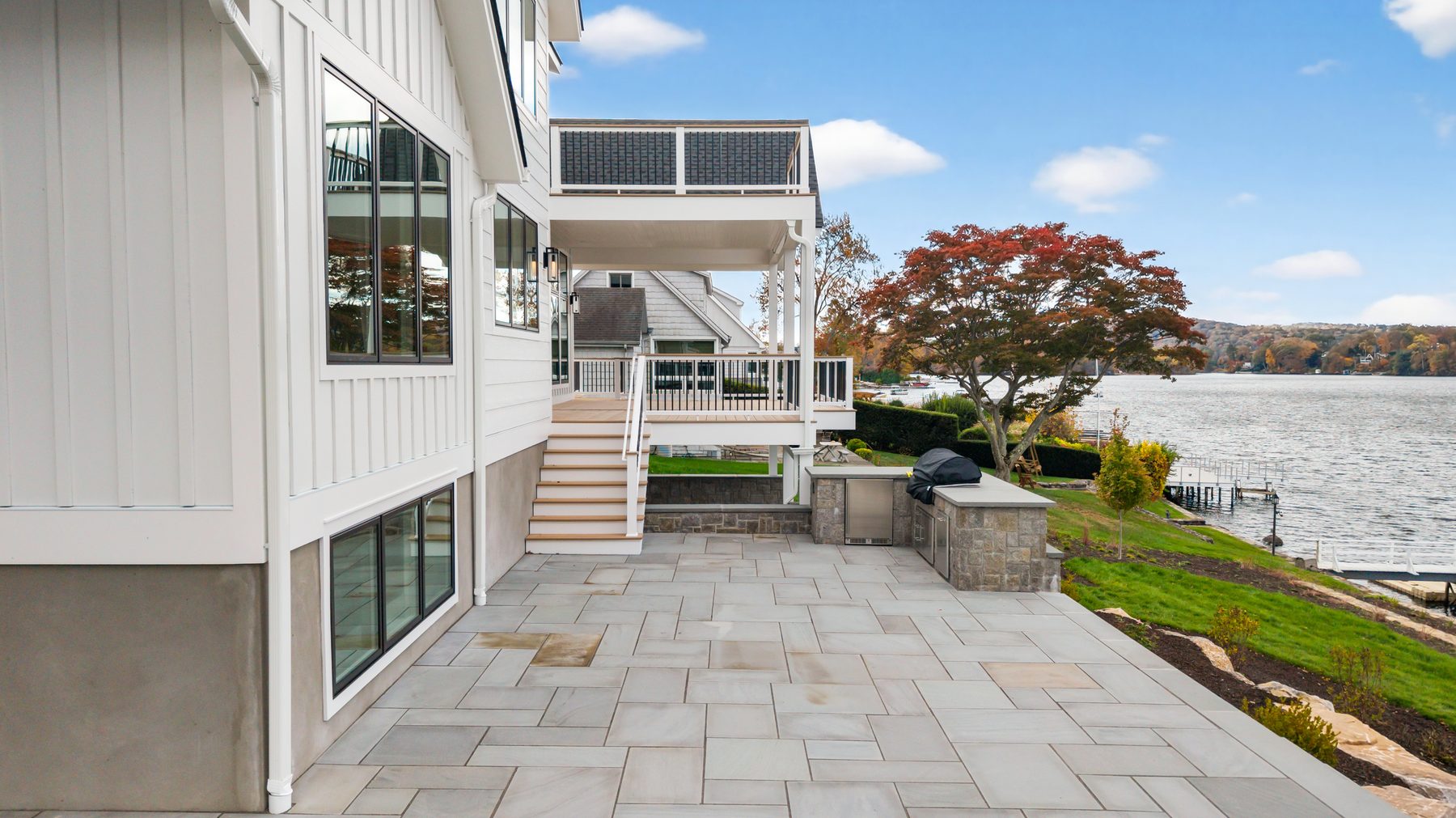 Lakeside rear elevation showing the patio, paver terrace, and stairs stepping down toward Candlewood Lake - 148 North Lake Shore in Candlewood Shores