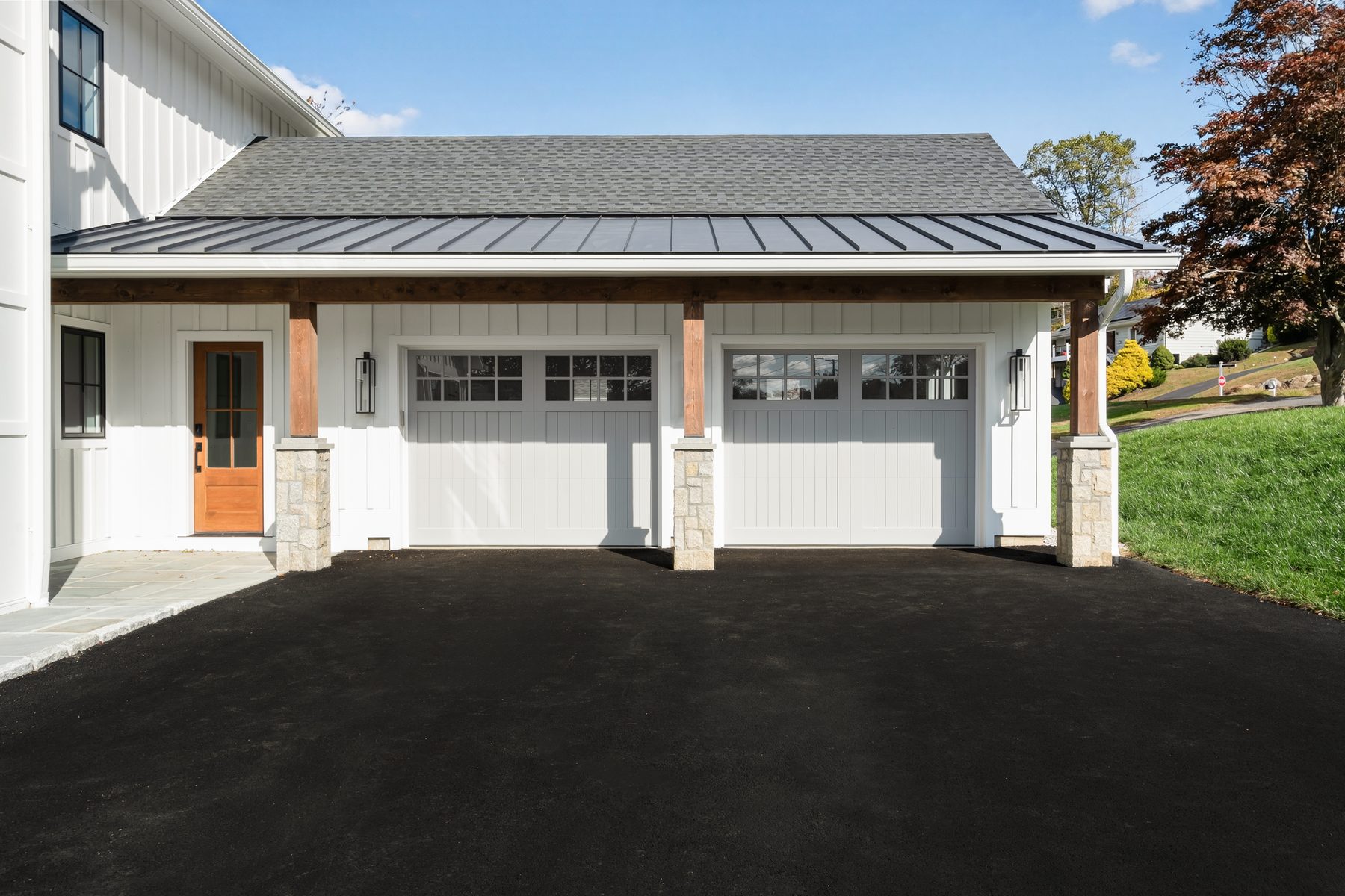 Front three-quarter view highlighting the metal-roofed garage wing and asphalt driveway approach - 148 North Lake Shore in Candlewood Shores on Candlewood Lake