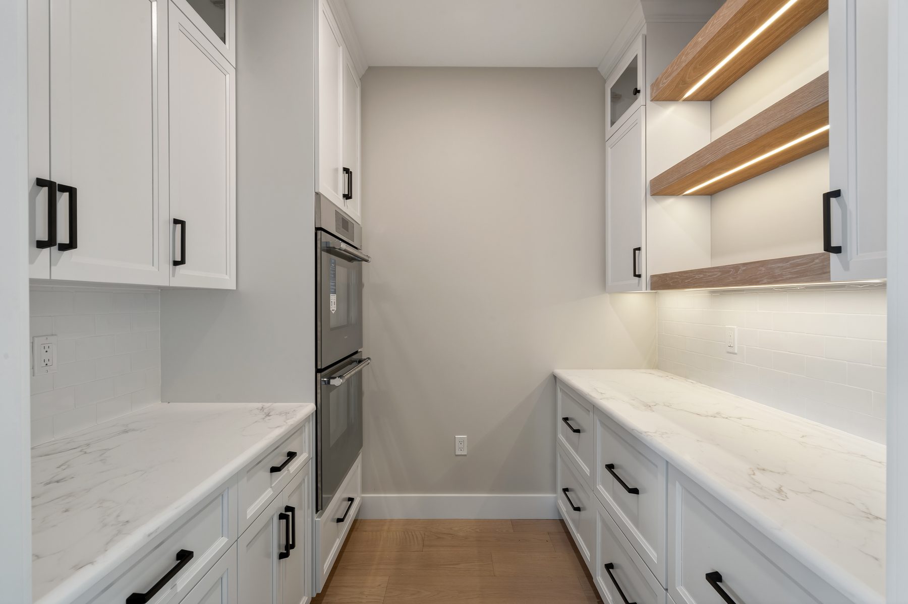 Butler's pantry with marble counters, subway-tile backsplash, double wall ovens, and LED-lit oak shelving - 148 North Lake Shore in Candlewood Shores on Candlewood Lake