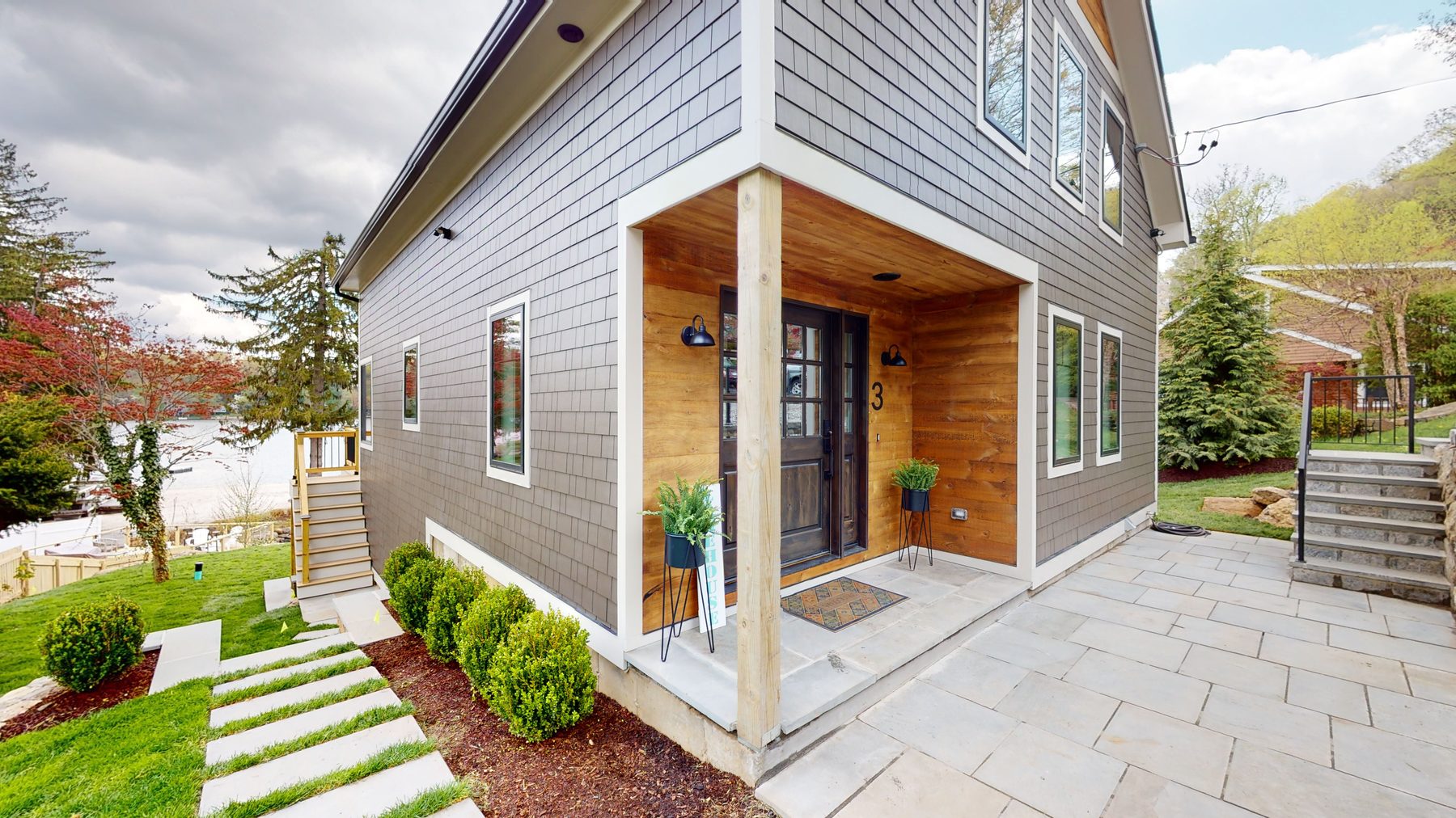 Covered front entry with wood-clad surround, house number three and a stepped stone path through fresh landscaping — 3 Woods Road, a custom lakefront home in Candlewood Knolls on Candlewood Lake