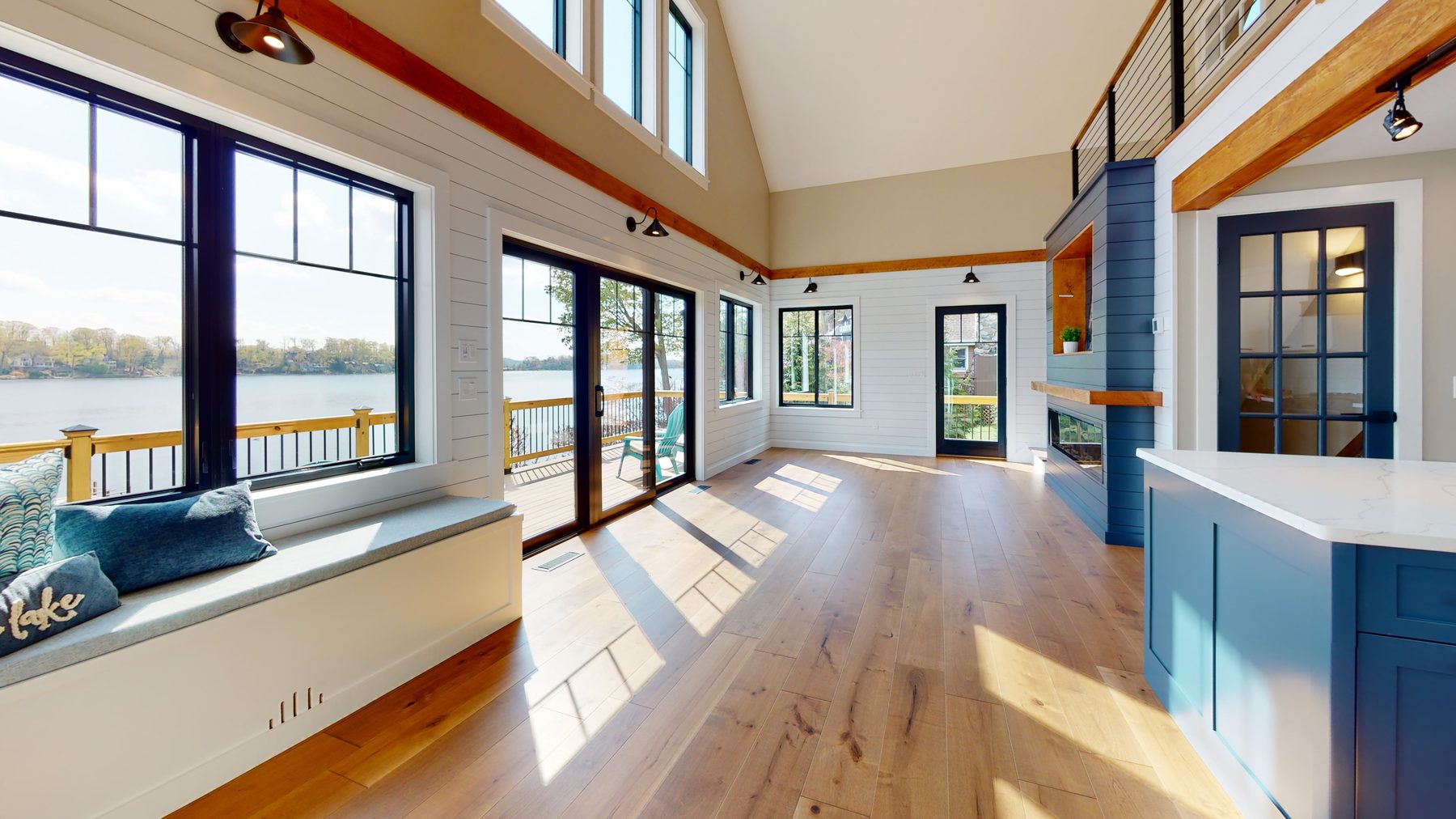 Kitchen and great room with a blue island, farmhouse sink and sliding doors framing the lake under a beamed vaulted ceiling — 3 Woods Road, a custom lakefront home in Candlewood Knolls on Candlewood Lake