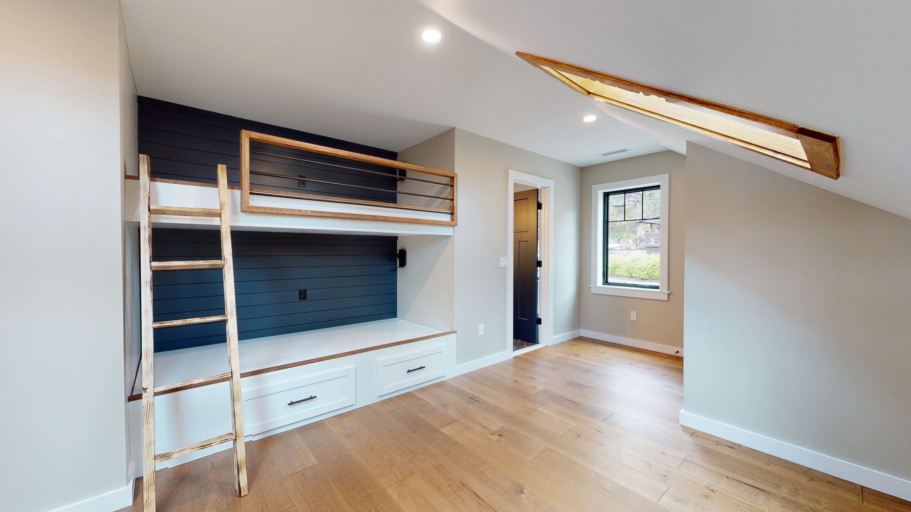 Built-in bunk room with navy shiplap, wood-framed berths and a ladder beneath a skylighted vaulted ceiling — 3 Woods Road, a custom lakefront home in Candlewood Knolls on Candlewood Lake