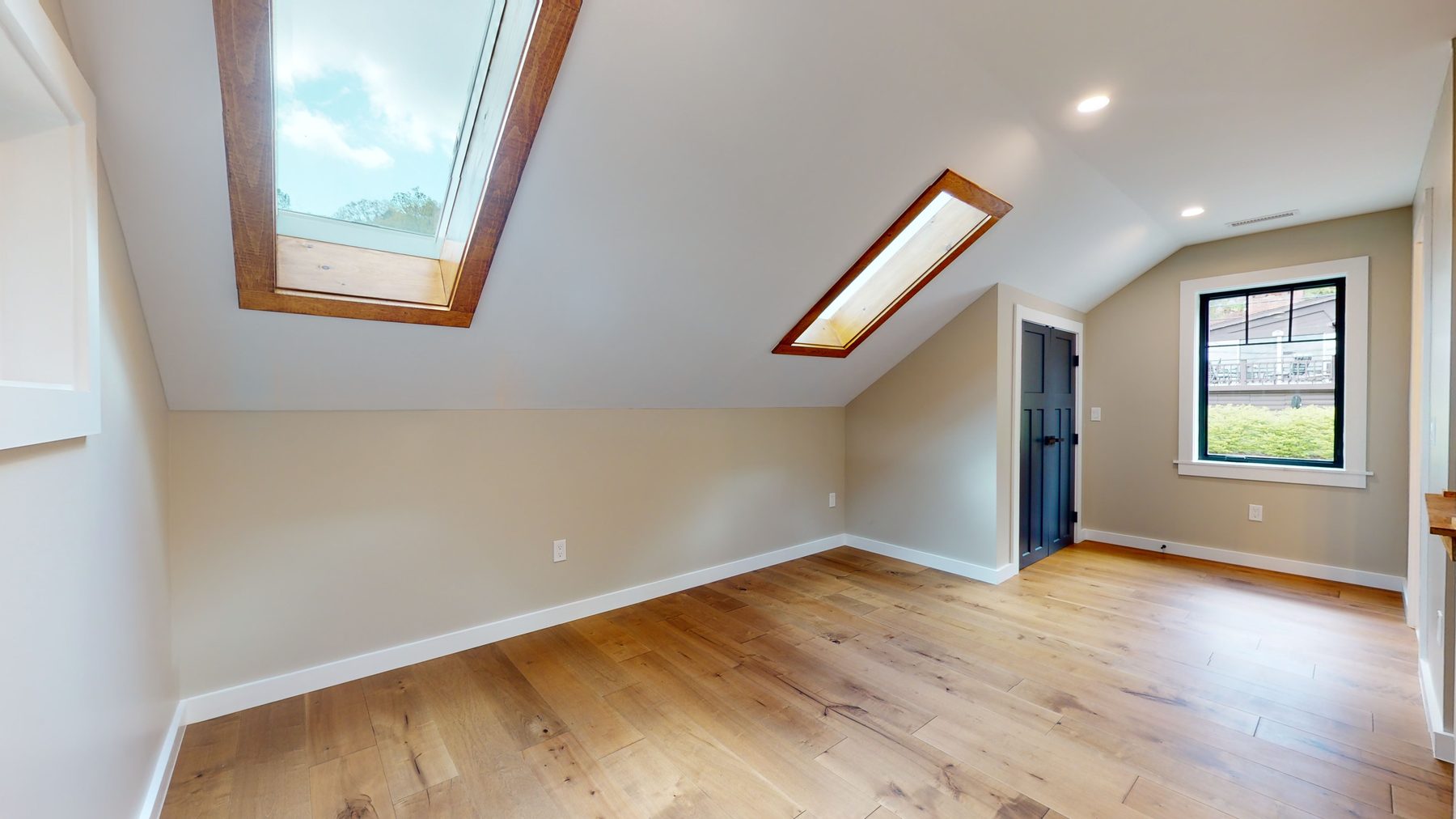 Sunlit bonus room with sloped vaulted ceilings, wood-trimmed skylights and a navy paneled door — 3 Woods Road, a custom lakefront home in Candlewood Knolls on Candlewood Lake