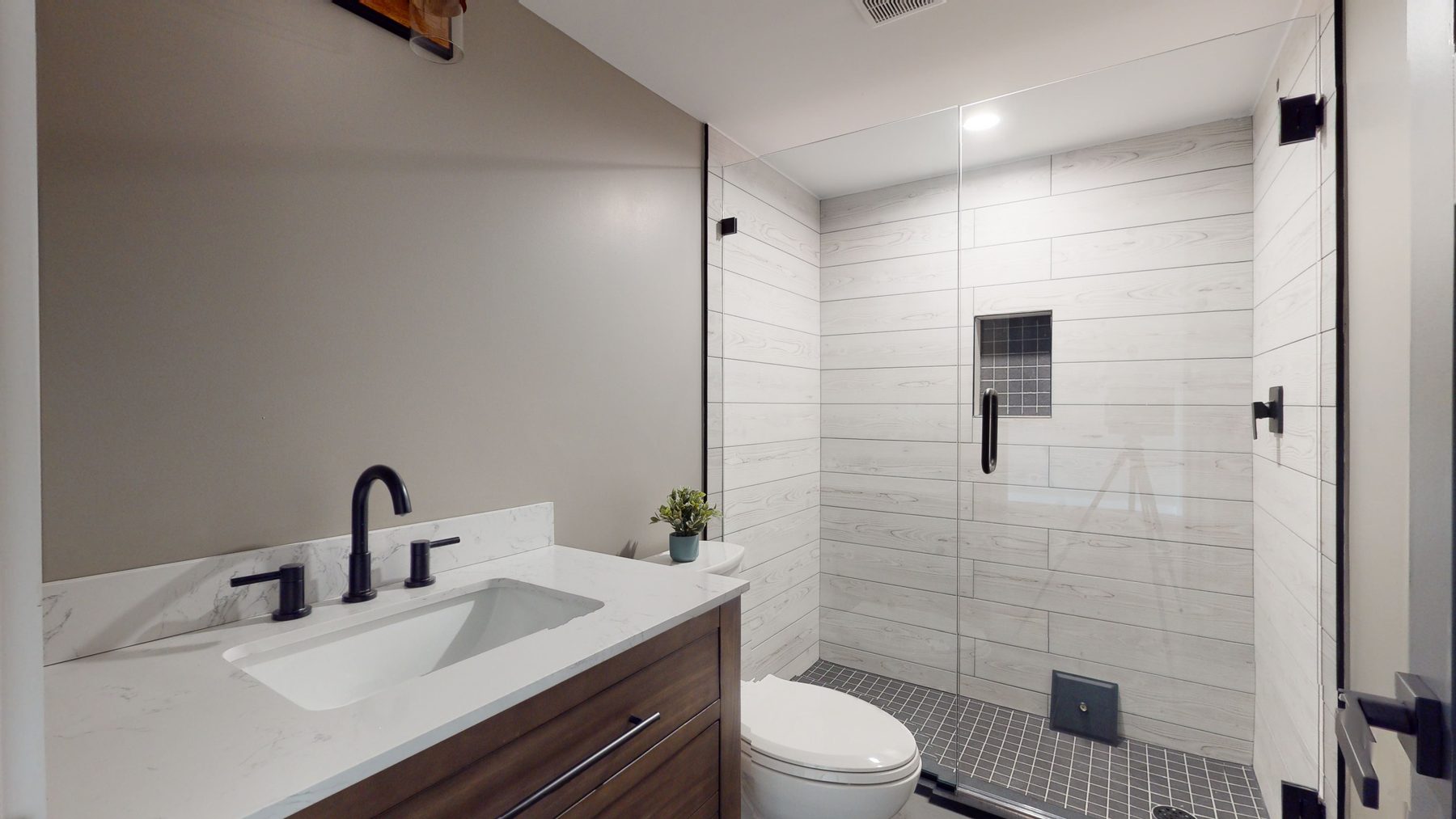 Full bath with a glass walk-in shower, wood-look tile, mosaic floor and a marble-look quartz vanity — 3 Woods Road, a custom lakefront home in Candlewood Knolls on Candlewood Lake