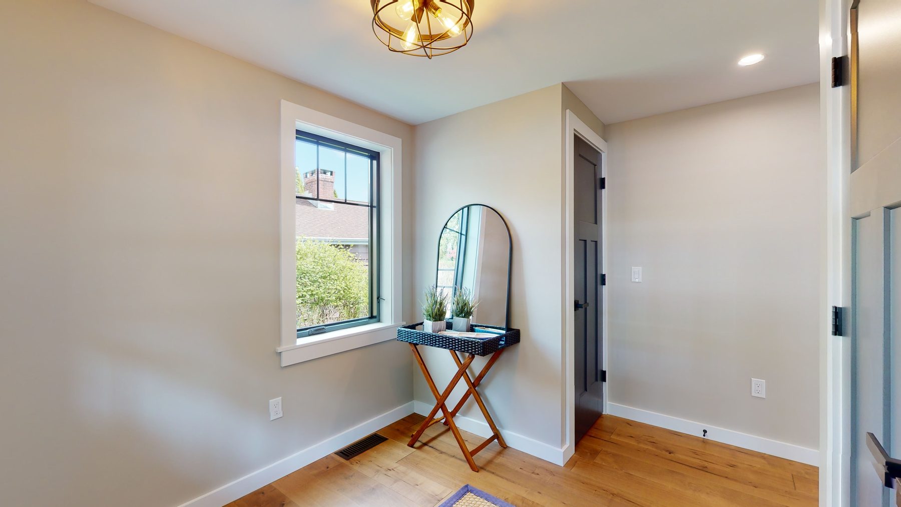 Bright entry nook with white oak floors, a window framing the wooded lot and a slate-blue paneled door — 3 Woods Road, a custom lakefront home in Candlewood Knolls on Candlewood Lake