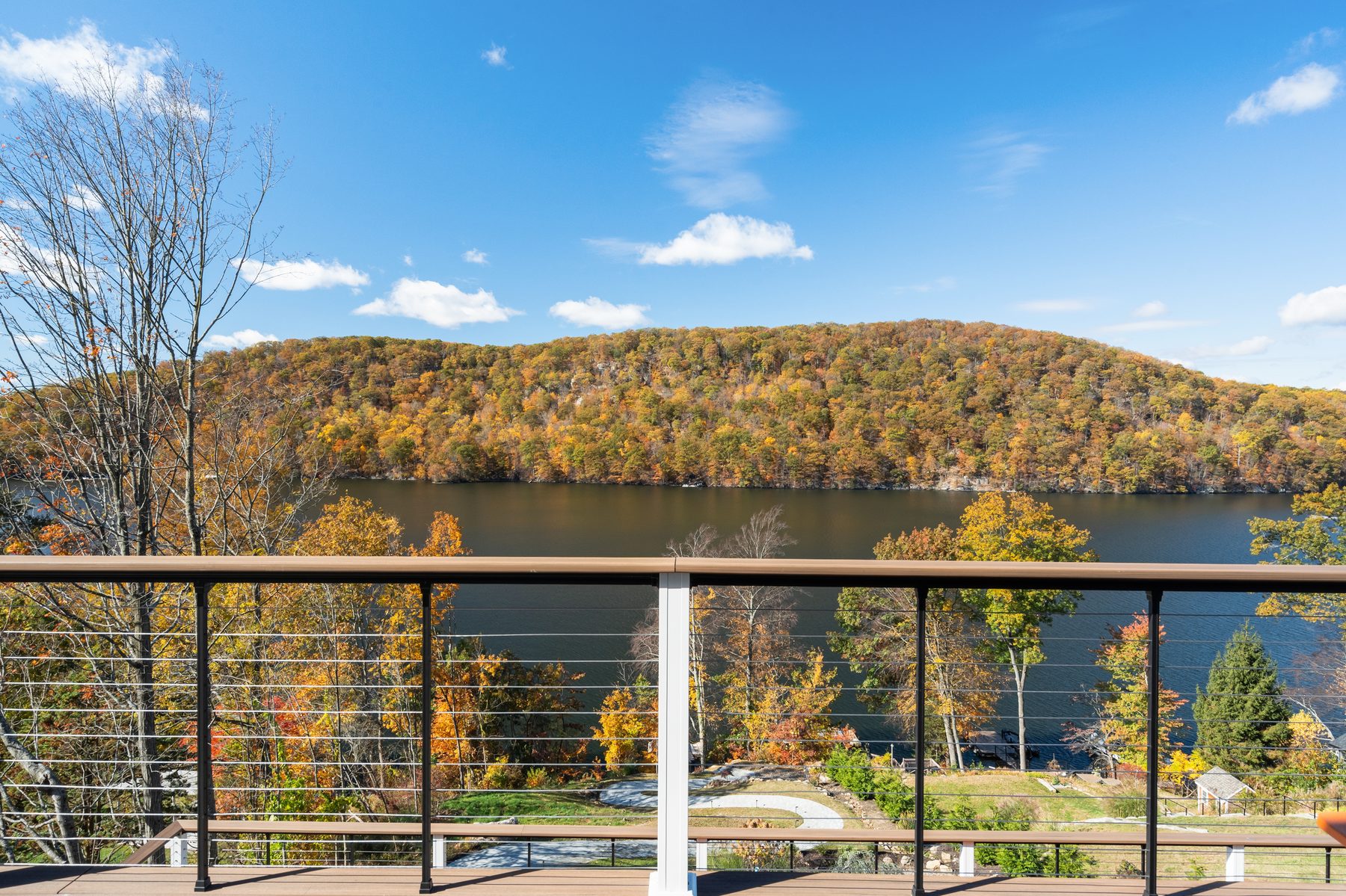Cable-railed deck framing autumn hillsides reflected across Candlewood Lake - 43 Moody Lane, a custom home in Danbury, CT