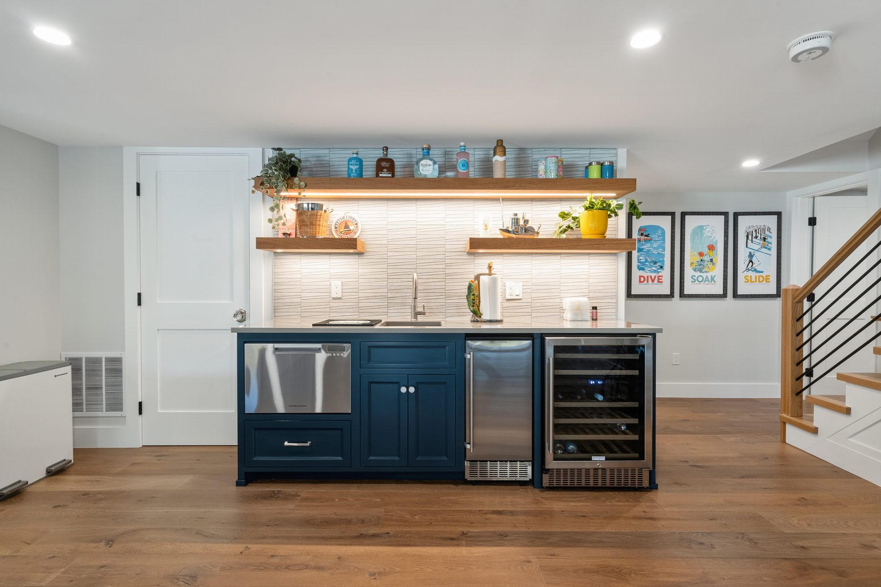 Lower-level wet bar with a navy-blue cabinet base, floating oak shelves and an under-counter wine fridge - 43 Moody Lane, a custom home in Danbury, CT