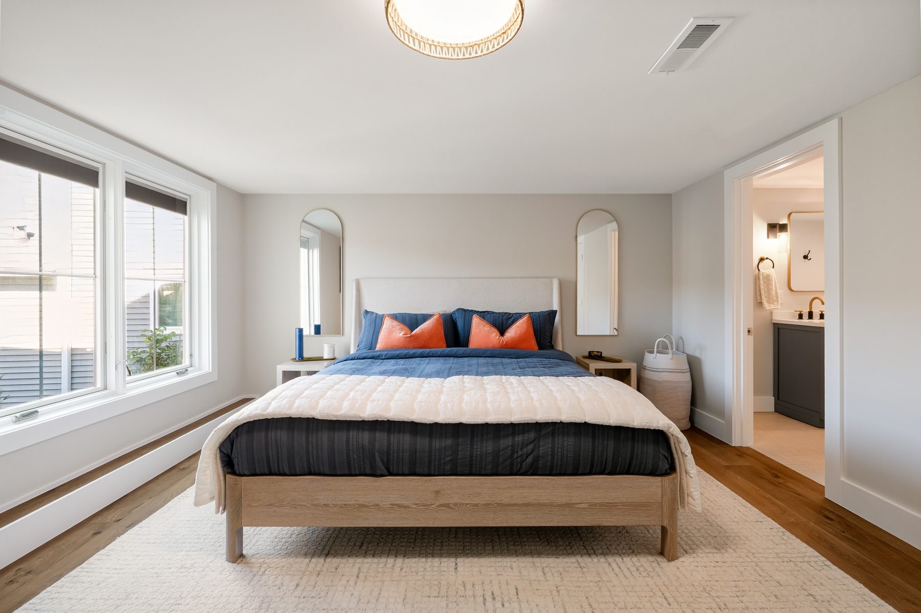 Staged guest bedroom with an upholstered bed, arched wall mirrors and an adjoining ensuite bath - 43 Moody Lane, a custom home in Danbury, CT