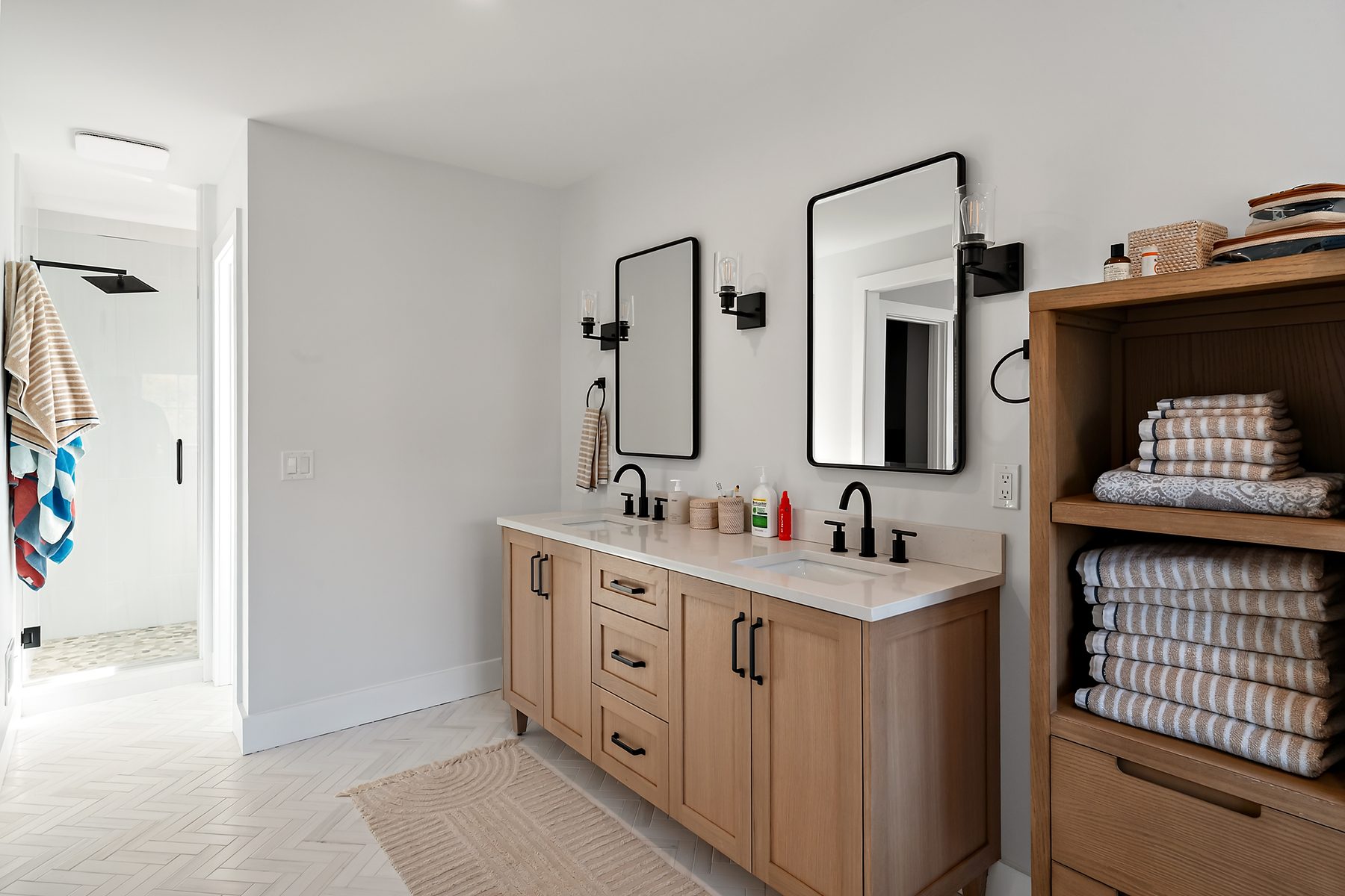 Primary bath with a walk-in glass shower, light-oak double vanity and herringbone tile flooring - 43 Moody Lane, a custom home in Danbury, CT
