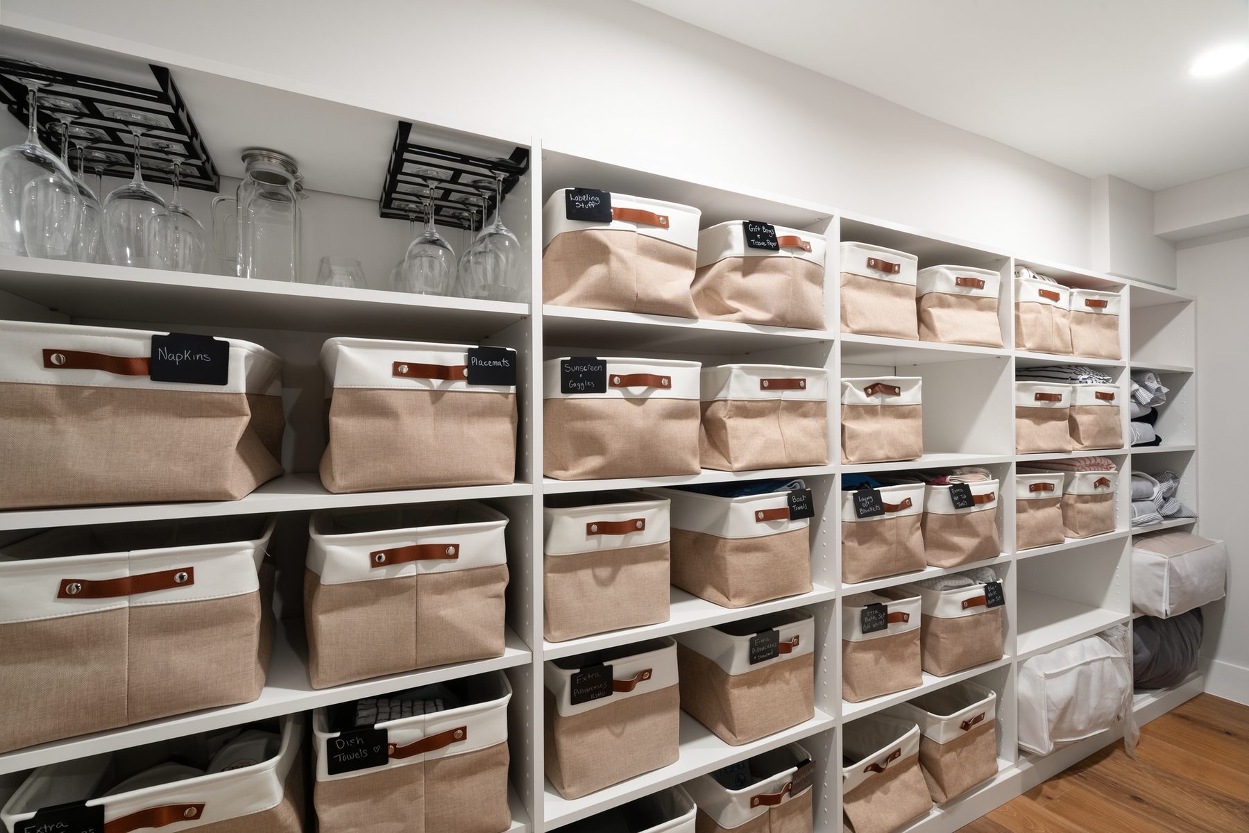 Organized walk-in pantry with white shelving, labeled storage bins and stemware racks - 43 Moody Lane, a custom home in Danbury, CT