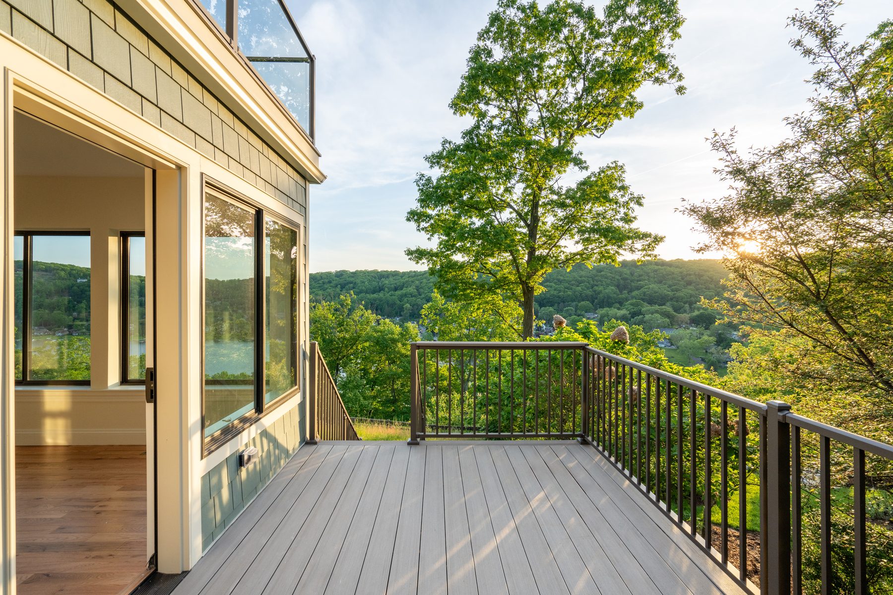 Composite lakeside deck with black metal railing framing hillside and water views at sunset - 48 Ridge Road, a renovated lake home with a second-floor addition on Candlewood Isle