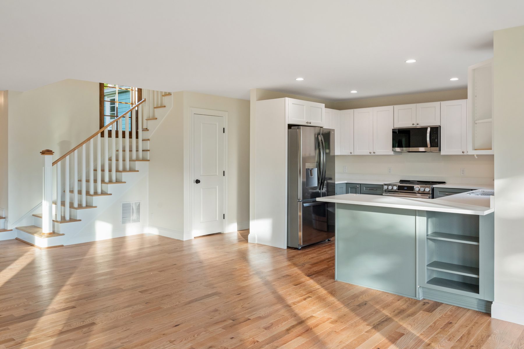 Open living and kitchen area with white staircase, oak floors and a stainless-and-shaker kitchen - 48 Ridge Road on Candlewood Isle