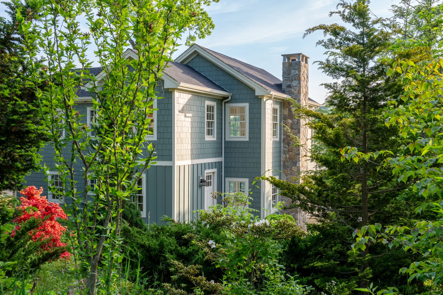 Architectural close-up of cedar-shake and board-and-batten siding meeting the fieldstone chimney of the second-floor addition - 48 Ridge Road on Candlewood Isle