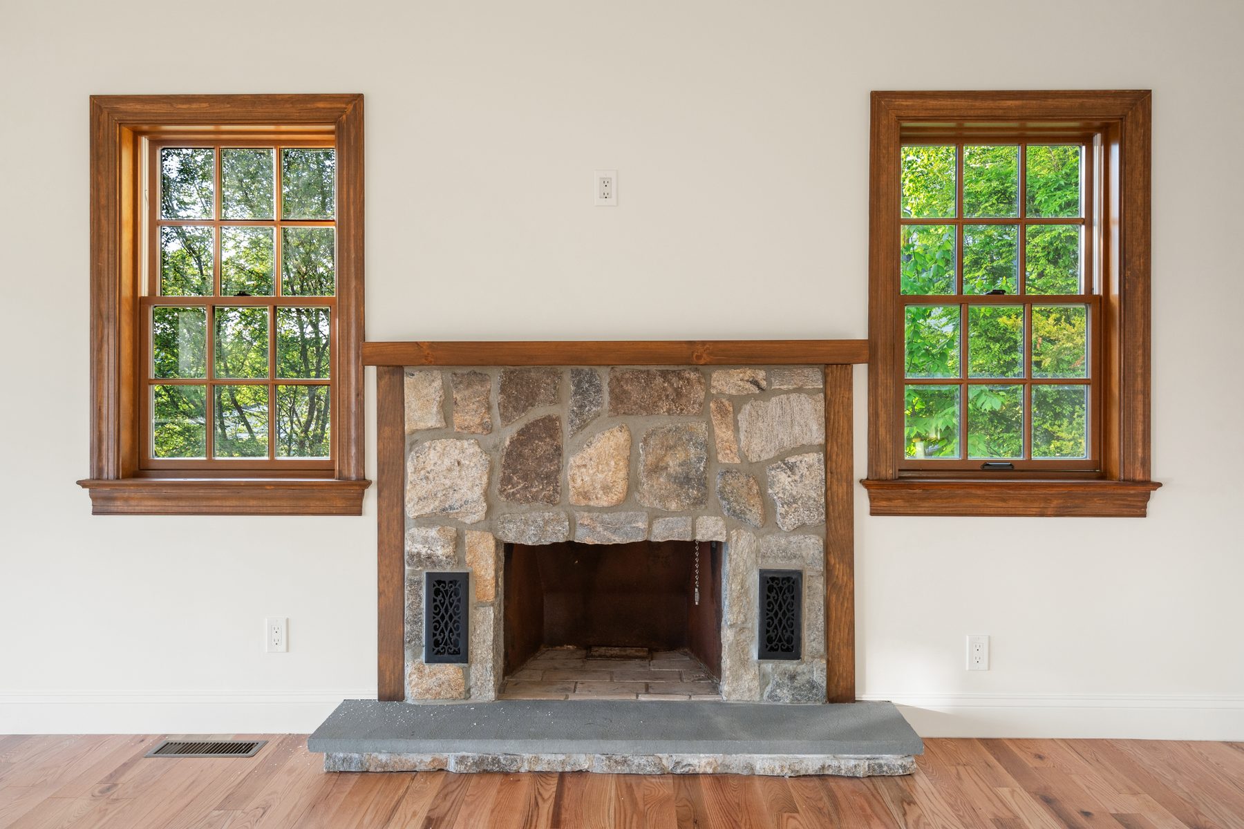 Fieldstone wood-burning fireplace flanked by stained divided-light windows in a light-filled room - 48 Ridge Road, a renovated lake home on Candlewood Isle