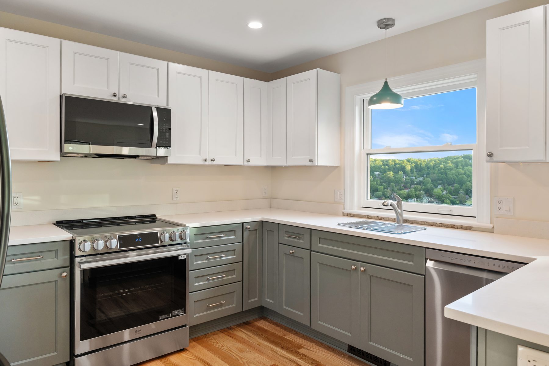 Corner of the renovated kitchen with sage-green cabinetry beneath a lake-view window and pendant light - 48 Ridge Road on Candlewood Isle