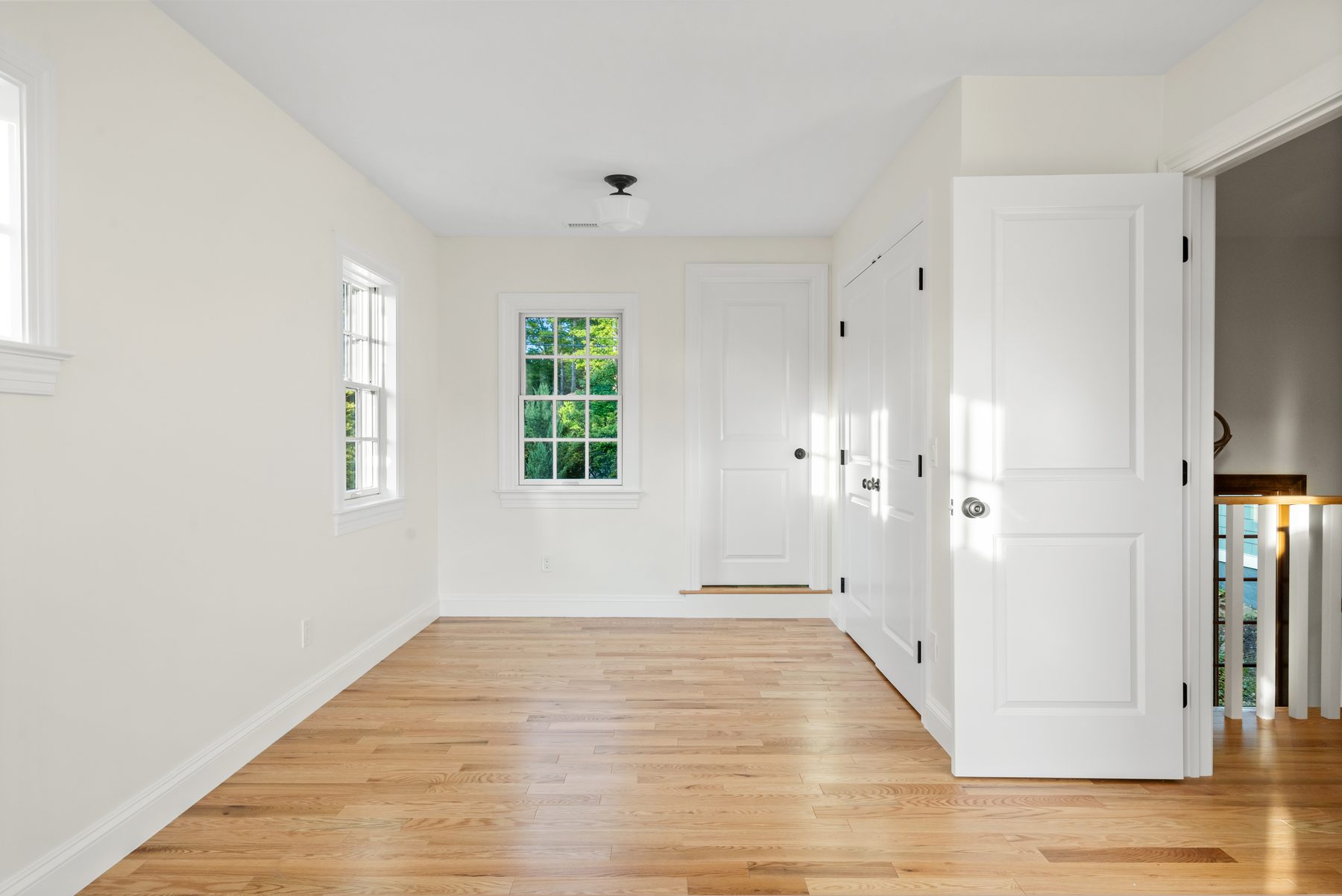 Light-filled bedroom with crisp white doors, built-in closets and a divided-light window over oak floors - 48 Ridge Road on Candlewood Isle