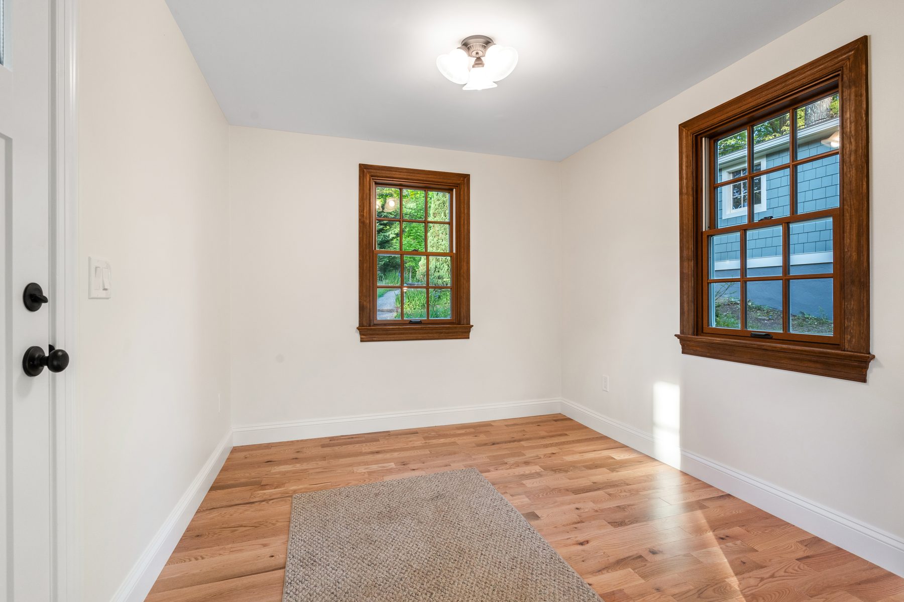 Corner room with stained-wood-trimmed windows pouring afternoon light across new oak flooring - 48 Ridge Road, a renovated lake home on Candlewood Isle