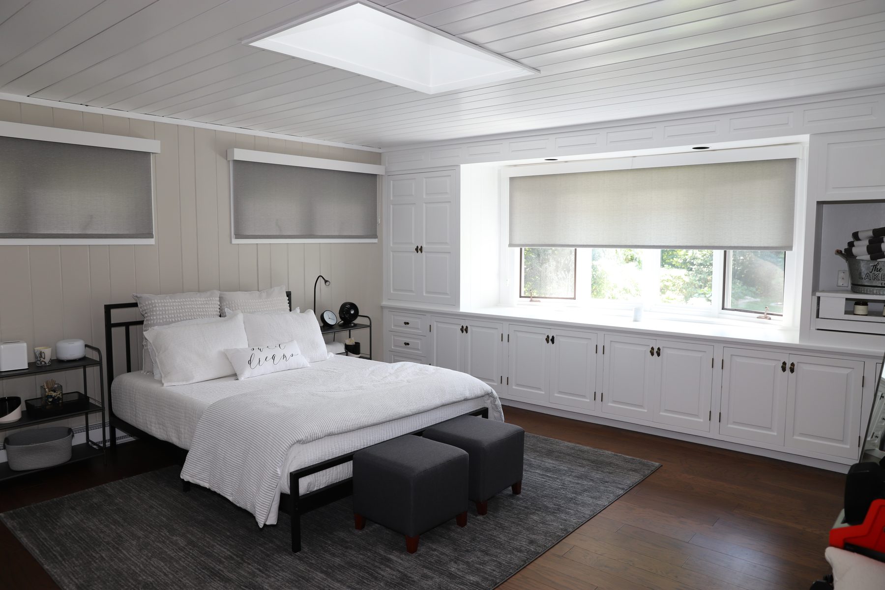 Primary bedroom in soft white with a skylight, plank ceiling and a long wall of built-in cabinetry - Sunset Drive, a renovated lake home on Candlewood Lake