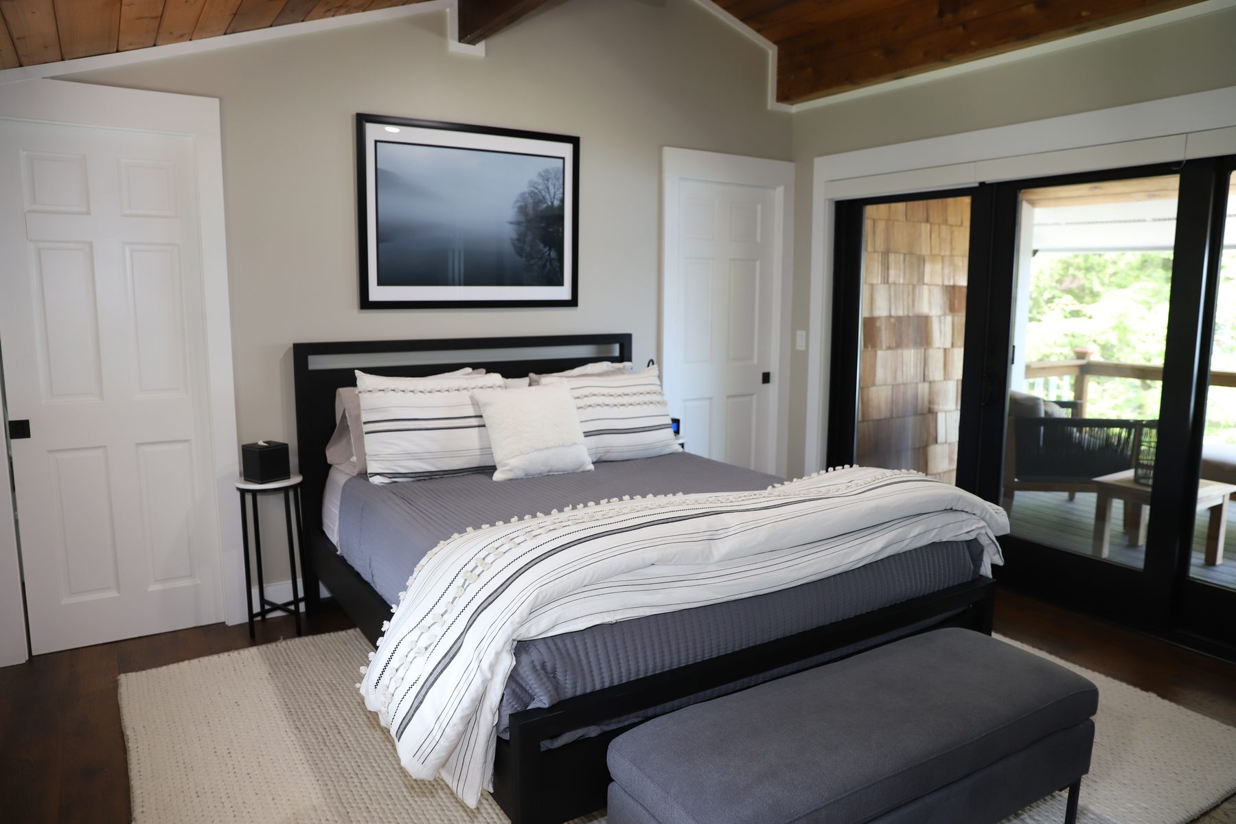 Guest bedroom with a vaulted wood ceiling and sliding doors opening to a private deck - Sunset Drive, a renovated lake home on Candlewood Lake