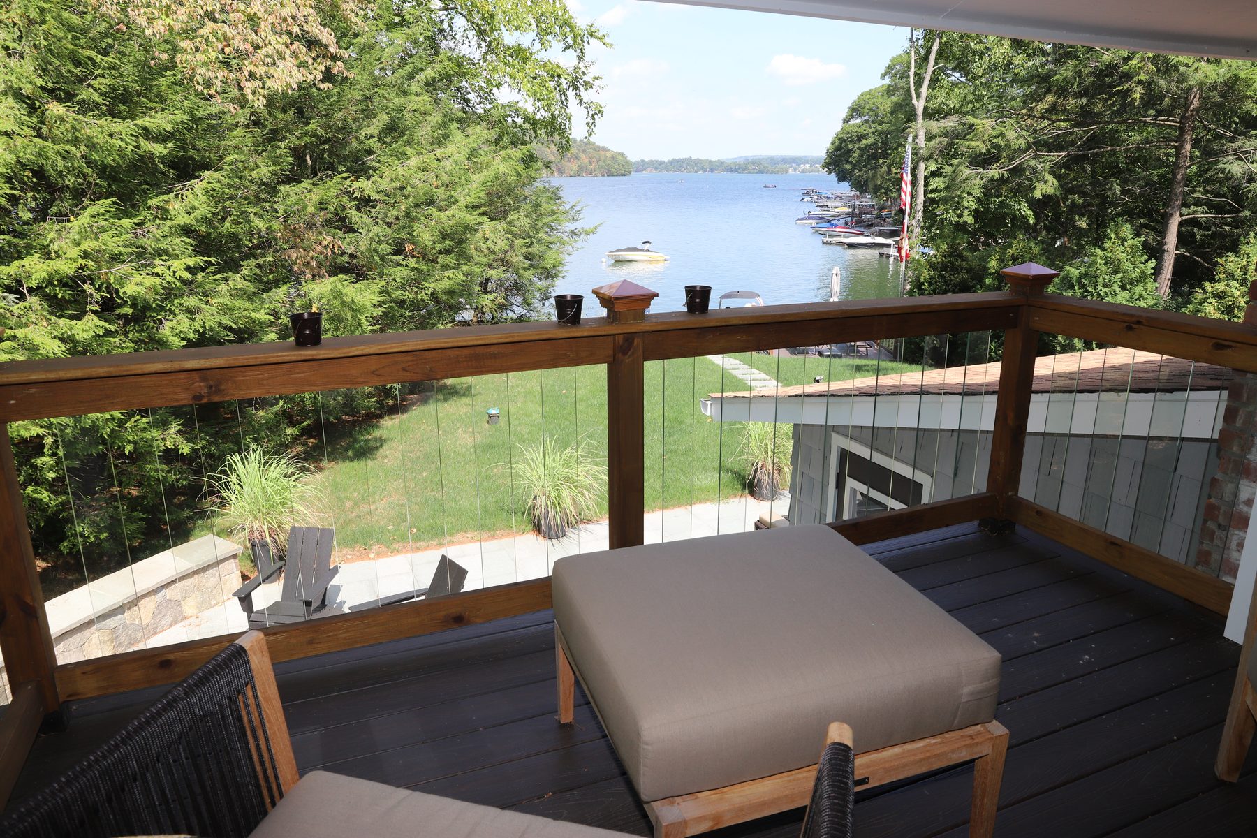 Covered deck with a cable-rail balustrade framing a sweeping treetop view over Candlewood Lake - Sunset Drive, a renovated lake home in Connecticut
