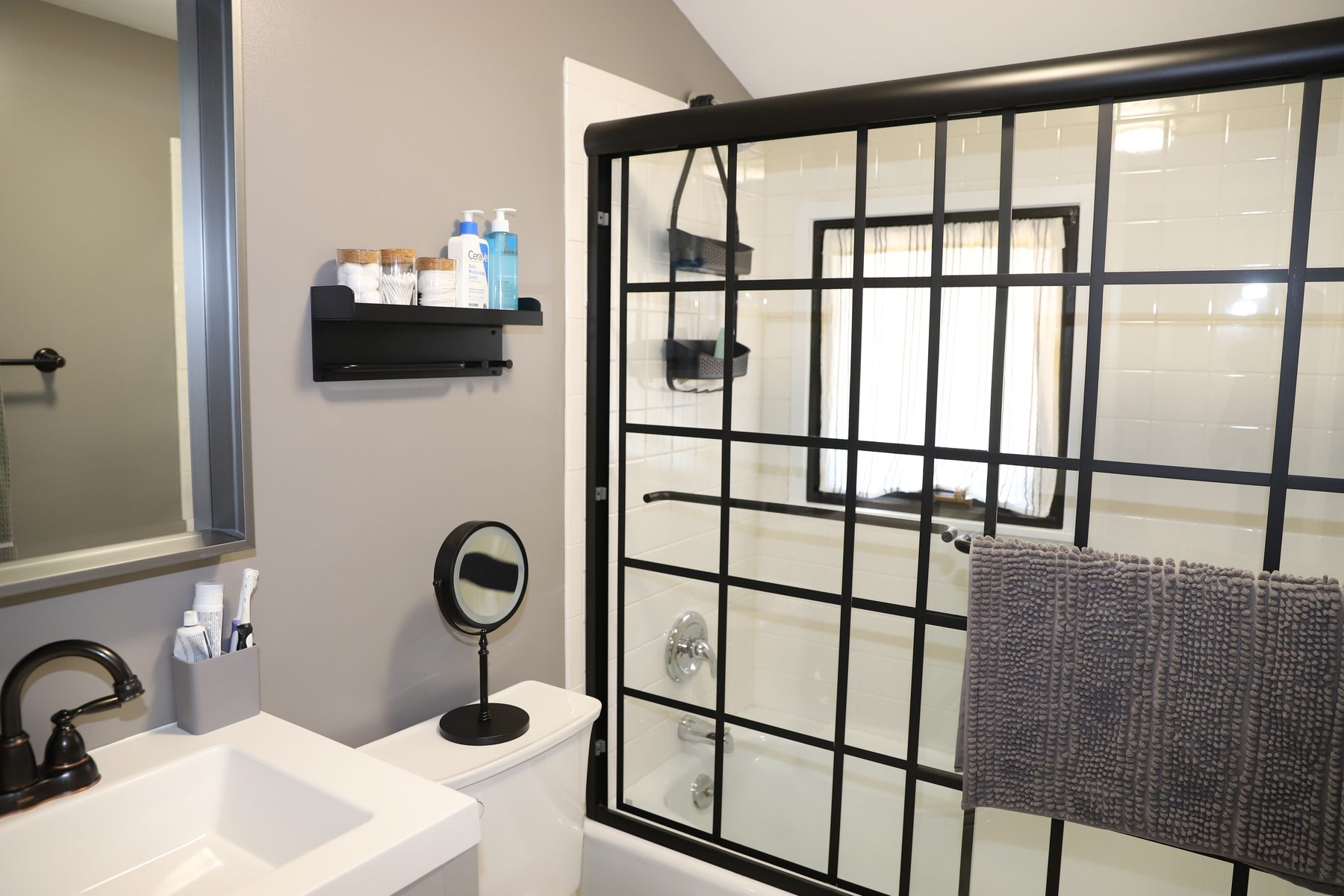 Bath with a black-grid glass shower enclosure, white subway tile and a clean white vanity - Sunset Drive, a renovated lake home on Candlewood Lake